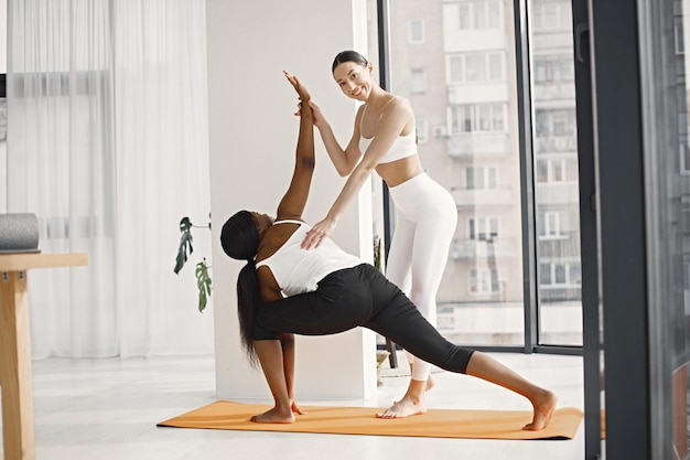 Black woman and caucasian female coach working out in studio with big windows