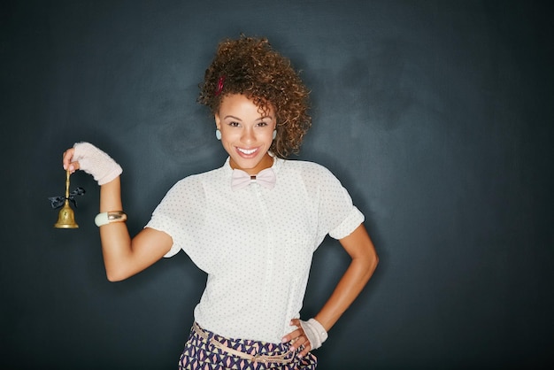 Black woman happy portrait and ring bell for mockup blackboard space for hospitality Female model with vintage teacher or waitress chime for advertising sale product placement or mockup service