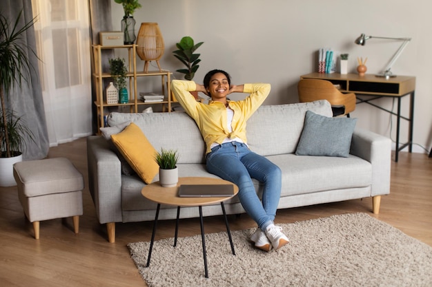 Black Woman Holding Hands Behind Head Sitting Relaxing At Home