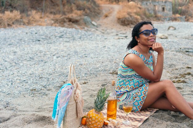 Black Woman is sitting on the beach with a glass of wine on summer vacation