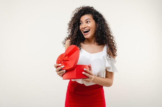 Black woman smiling with red heart shaped valentine gift box isolated