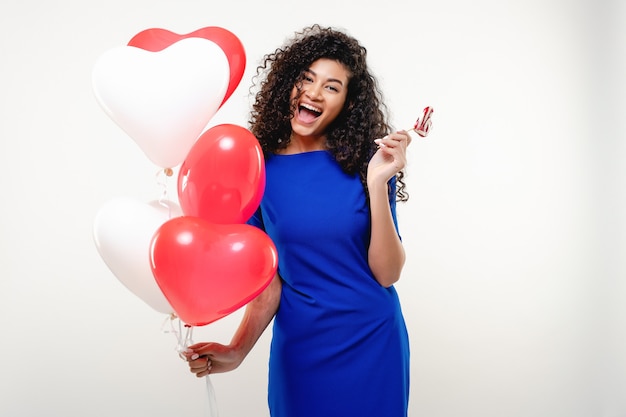 Black woman with heart shaped lollypop candy and colorful balloons isolated