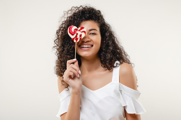 Black woman with heart shaped lollypop candy wearing red skirt isolated