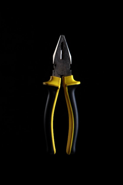 Black and yellow pliers, wire cutters on black background