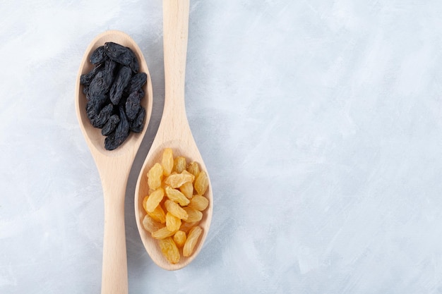 Black and Yellow raisins in wooden spoons Dried dehydrated grapes fruit