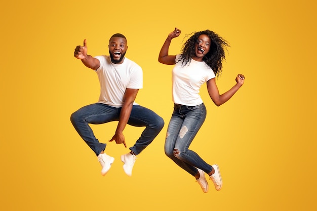 Black young couple having fun on yellow studio background