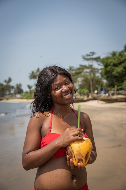 A black young smiling lady with black long hair at the beach on holiday