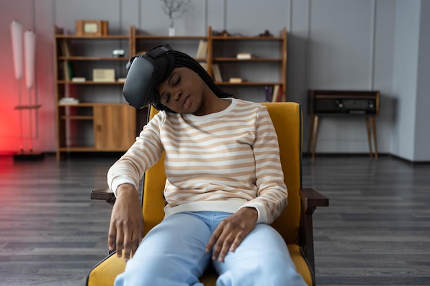 Black young woman removed virtual reality goggles and fell asleep after watching series in armchair