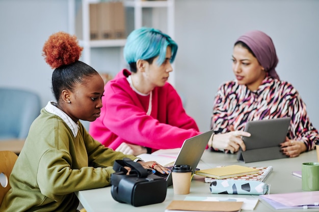 Black young woman using laptop during meeting in office