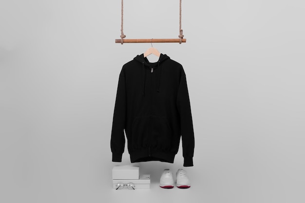 Black zip hoodie hanging on wood hanger isolated on plain background