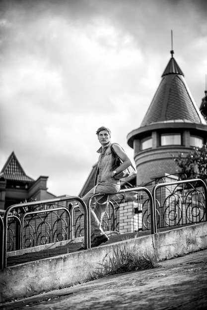 Blackandwhite photo of a fashion guy with a bag sitting on the rails