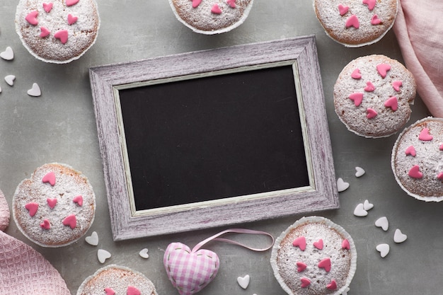 Blackboard framed with sugar-sprinkled muffins with pink and white fondant icing hearts