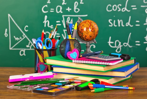 blackboard with pencil-box and school equipment on table