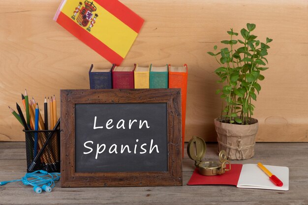 Blackboard with text Learn Spanish flag of the Spain books pencils compass