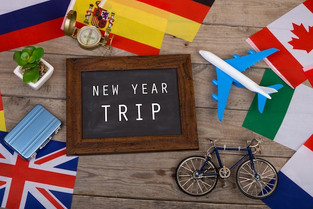 Blackboard with text New Year trip flags of different countries airplane model little bicycle