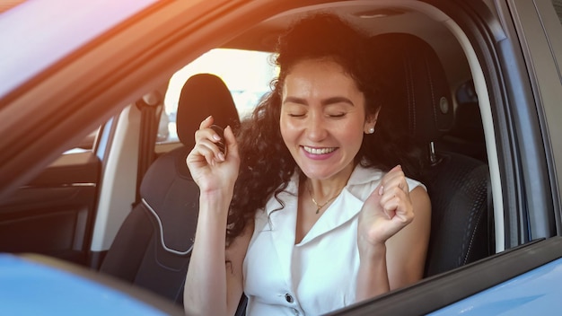 Blackhaired woman enjoys new purchase sitting at car wheel