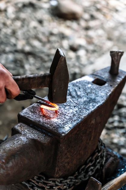 Photo blacksmith in a forge at work on an anvil hot metal forging