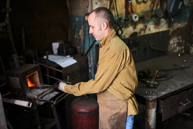 The blacksmith in the production process of metal products handmade in the workshop