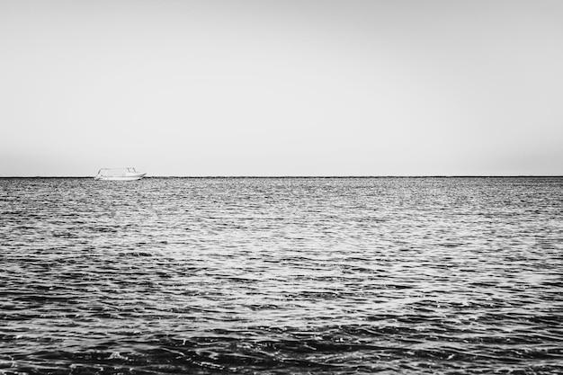 Blackwhite photography alone blurred boat or ship in silent sea or ocean water