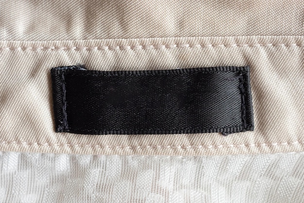 Blank black laundry care clothing label on fabric texture