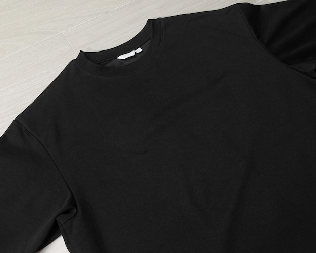 Blank Black Oversized T-shirt mockup template on the floor.