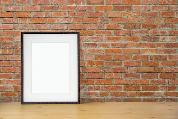 Blank black picture frame on the red brick wall and the wooden floor