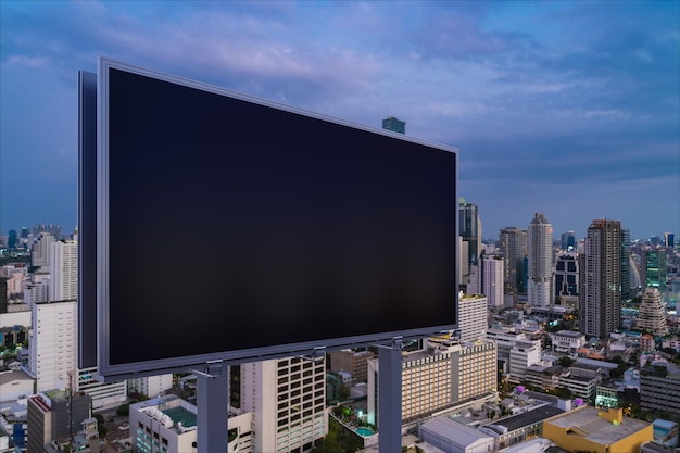 Blank black road billboard with Bangkok cityscape background at night time Street advertising poster mock up 3D rendering Side view The concept of marketing communication to promote idea