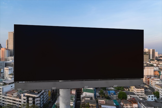 Blank black road billboard with Bangkok cityscape background at sunset Street advertising poster mock up 3D rendering Front view The concept of marketing communication to promote or sell idea