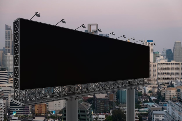 Blank black road billboard with Bangkok cityscape background at sunset Street advertising poster mock up 3D rendering Side view The concept of marketing communication to promote or sell idea