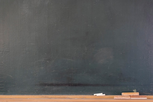 Blank blackboard with colored chalks and eraser and light effect