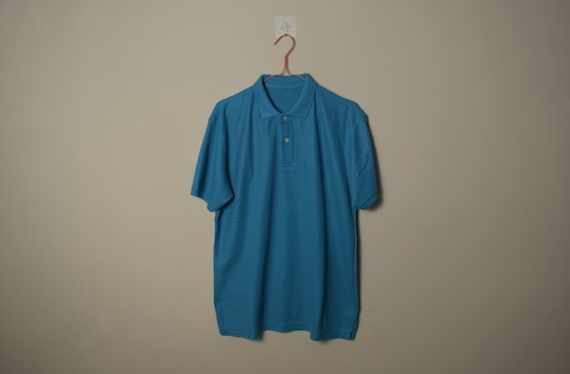 Blank blue casual TShirt Mockup on hanger at wall background front side view