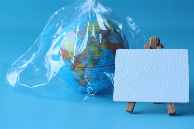 Blank board for text with a globe wrapped in a plastic bag. World Environment Day concept.