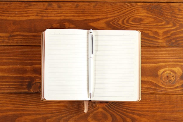 Blank brown notepad on a brown wooden table Business Wallpaper