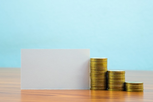 Blank business card or name card and stack of coin on table