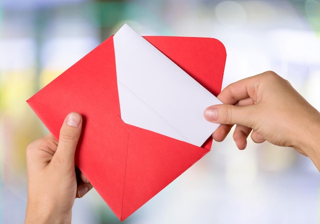 Blank card and envelope in hands on blurred background