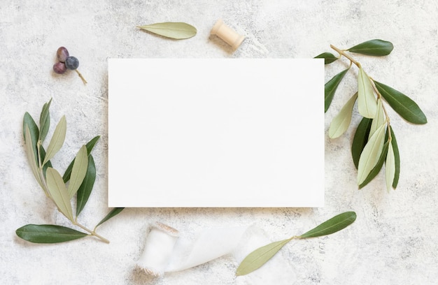 Blank card on marble table with olive tree branches