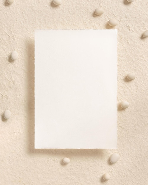 Blank card near pebble stones top view on beige mockup Romantic scene with vertical card