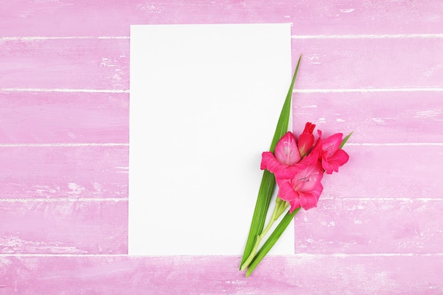 Blank card with beautiful gladiolus on wooden background