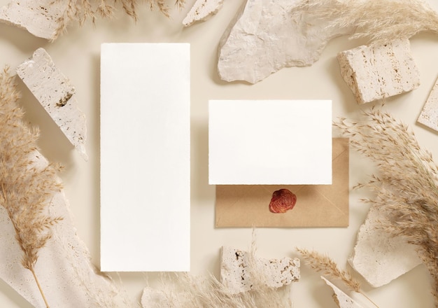 Blank cards near beige travertine stones and dried pampas grass top view greeting mockup