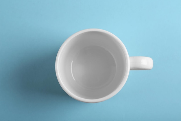 Blank ceramic cup on color background