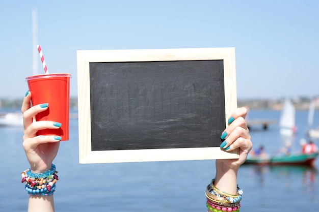 Blank chalkboard in female hand on beach background