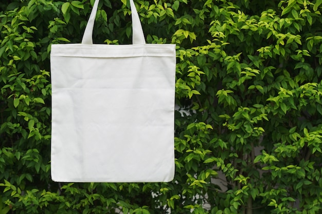 Blank fabric bag hanging on green leaf