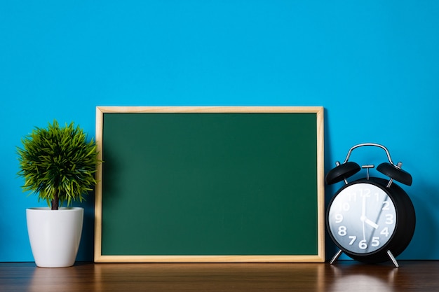 Blank green chalkborad and little decorative tree and vintage alarm clock