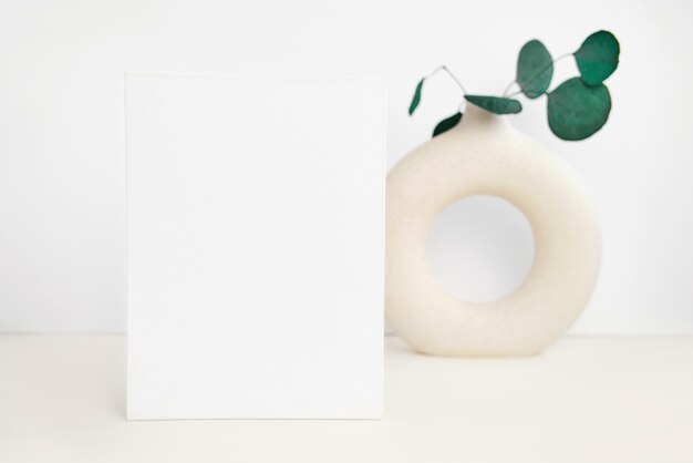 Photo blank greeting card invitation mockup front view eucalyptus branche in modern ceramic vase on table copy space paper mock up minimal business brand template soft shadow nordic flier design ad