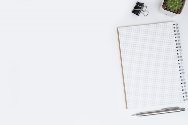 Blank grid lines notebook page on top of white office desk table. Top view, flat lay.