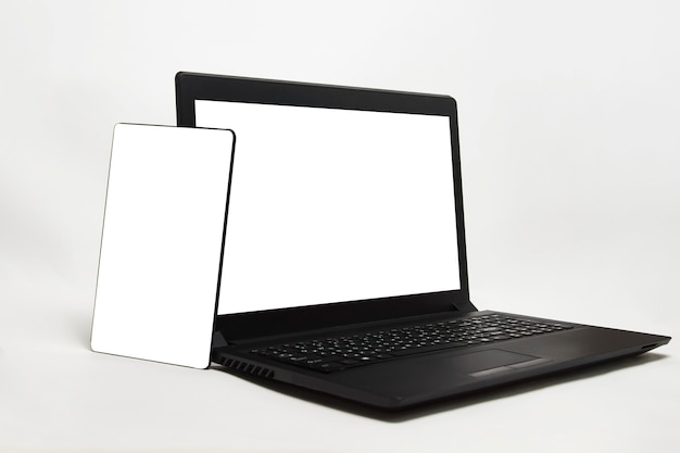 Blank laptop display and mobile phone on white background with copy space. Modern gadgets laptop, digital tablet and smartphone mockup with empty white screen