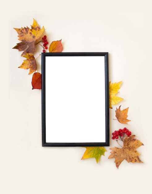 Blank mock up photo frame autumn leaves and berries on beige background flat lay top view copy space