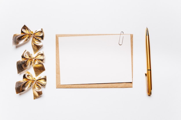 Blank note with envelope, bow and gold pen on white