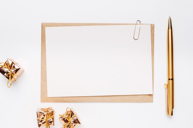 Blank note with pen and gifts on white background