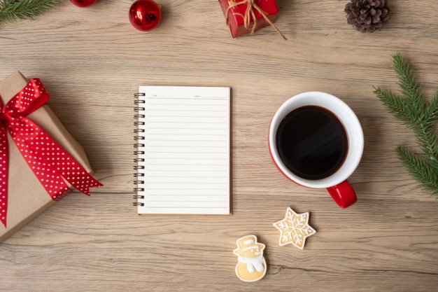 Blank notebook, black coffee cup, Christmas cookies and pen on wood table, Top view and copy space. Xmas, Happy New Year, Goals, Resolution, To do list, Strategy and Plan concept